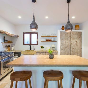 Modern rustic kitchen with wooden stools and pendant lights.