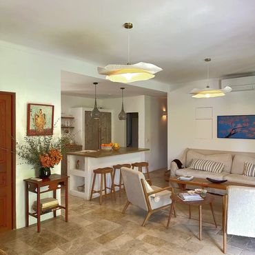 Cozy living room and kitchen area with warm lighting and wooden furniture.