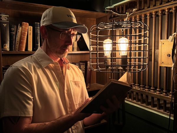 Aaron Reno is reading a book by lamp light at The Last Bookstore in Los Angeles, California.