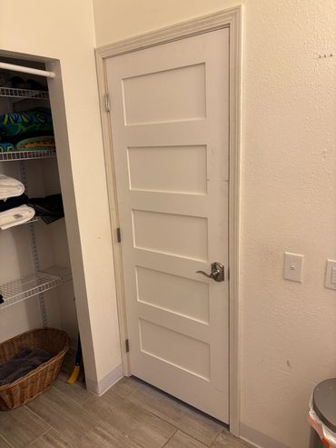 White paneled door in a laundry room with shelves and baskets.