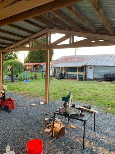 Outdoor woodworking area with tools and a green yard.