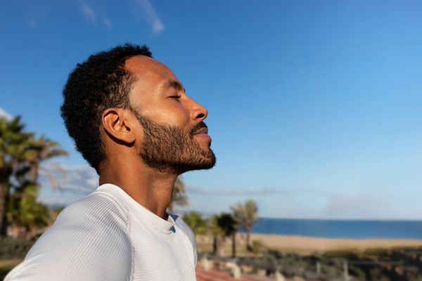 The image shows a man with dark skin and a beard, with his eyes closed and his head slightly.