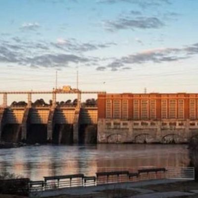 Hydroelectric dam at sunset with calm water.