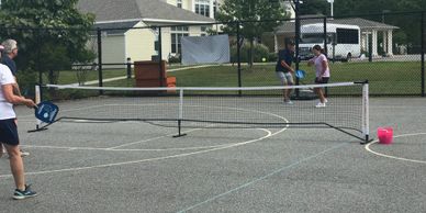 People playing pickleball on an outdoor court with a portable net.
