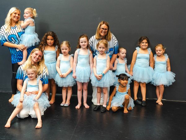 Group photo of young ballet dancers in blue tutus with their instructors.