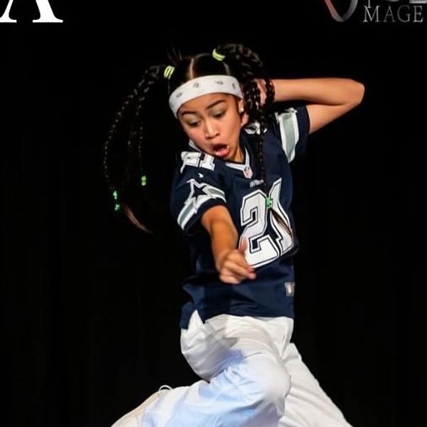 Young dance teacher Coco Wahana performing an energetic move on stage.