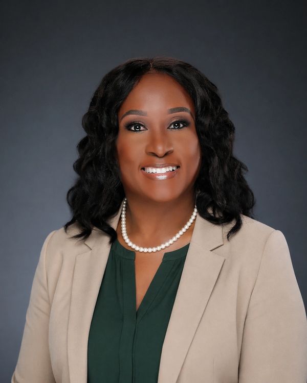 Professional woman smiling, dressed in beige blazer and pearl necklace.