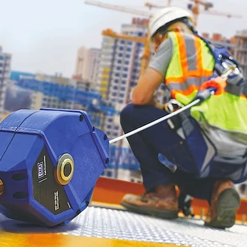 Trabajador de construcción con equipo de seguridad cerca de una herramienta azul.