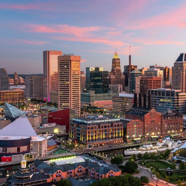 Baltimore city skyline at sunset with colorful sky and waterfront buildings.