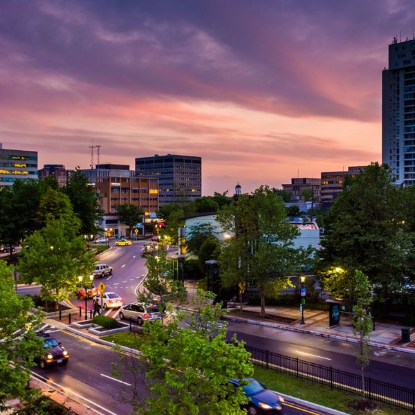 Cityscape at dusk with illuminated buildings and a colorful sky.