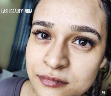Close-up of a woman's face showcasing long eyelash extensions and natural eyebrows.