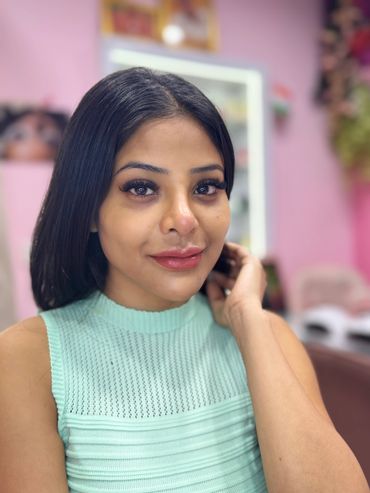 Young woman with straight black hair wearing a mint green sleeveless top.