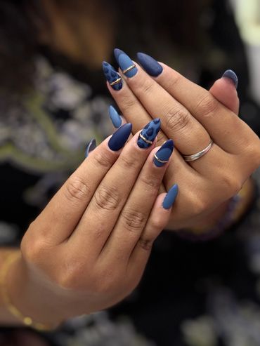 Matte blue nails with leopard print and gold accents on almond-shaped nails.