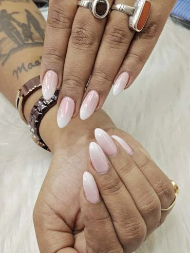 Elegant almond-shaped nails with a soft pink to white ombre effect.