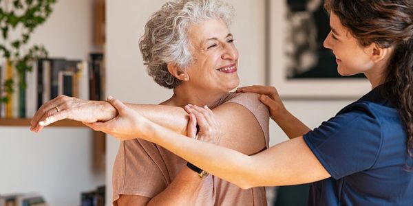 A physiotherapist is working with an senior woman helping her increase mobility.
