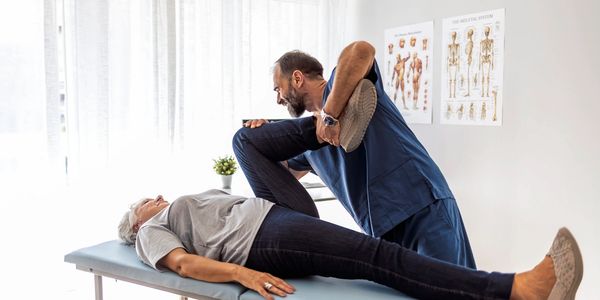 A chiropractor is working with a patient pressing her leg up against her body.