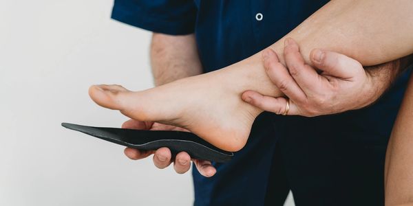 A podiatrist is adjusting an orthotic insole for a patient. 