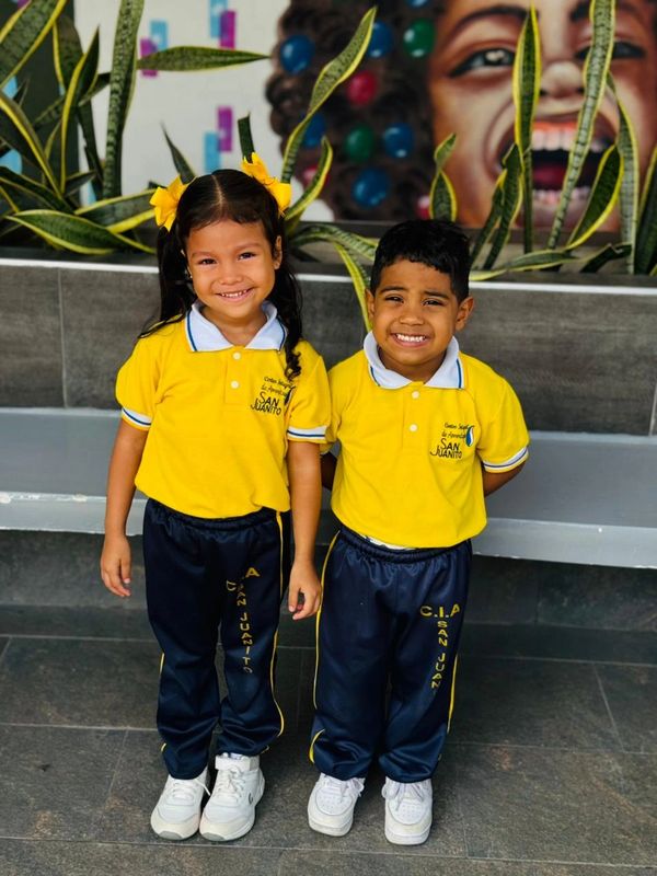 Dos niños sonrientes con uniforme amarillo y azul.
