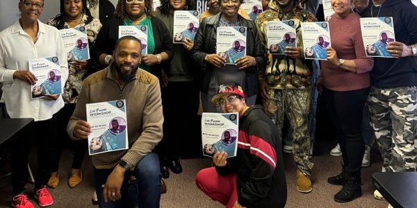 A group holds workshop certificates, smiling together indoors.