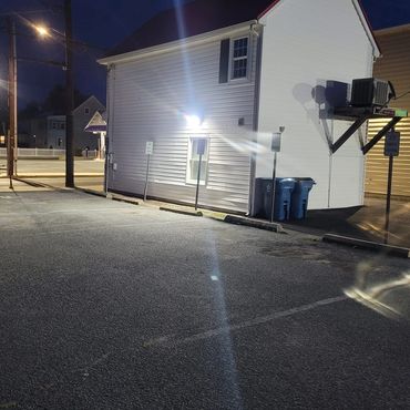 Empty parking lot beside a white building illuminated at night.