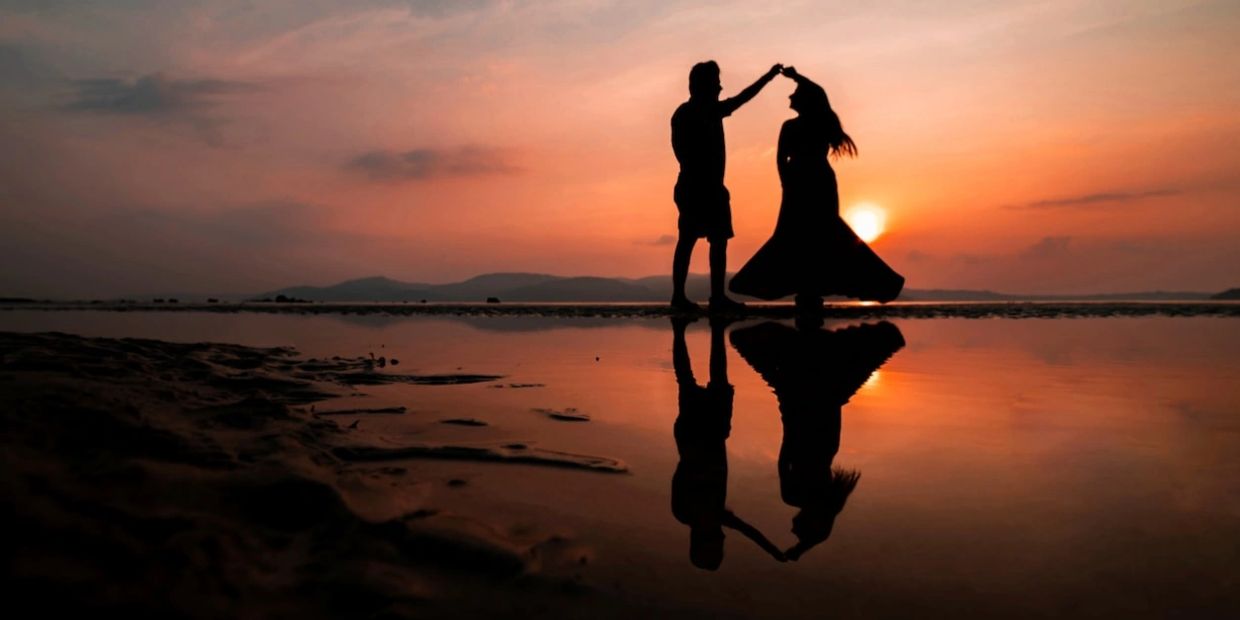 young couple dancing at sunset on beach