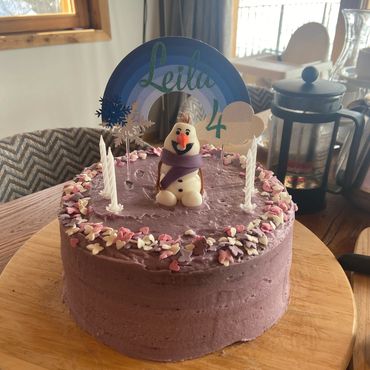 Purple birthday cake with Olaf figure and candles.