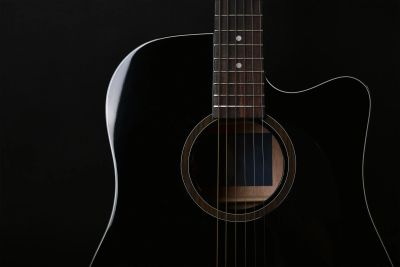 Close-up of a black acoustic guitar with strings and sound hole.