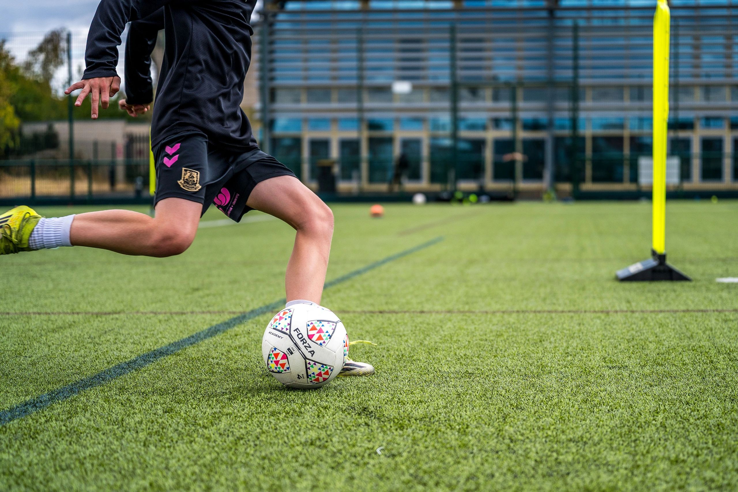 Soccer player kicking a ball on a green field.