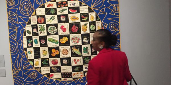 Person admiring colorful art with fruit and vegetable illustrations.