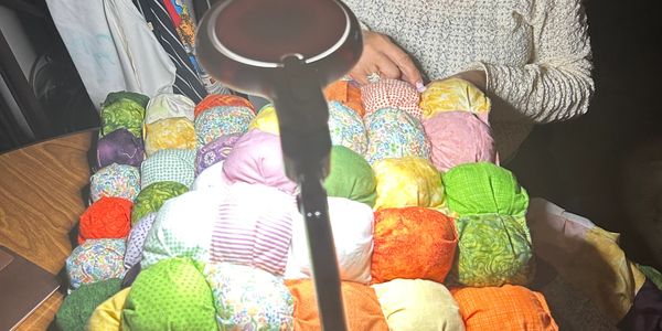 Person holding a colorful patchwork quilt.