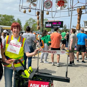 Person at an outdoor event wearing a sign about walking 754 miles.
