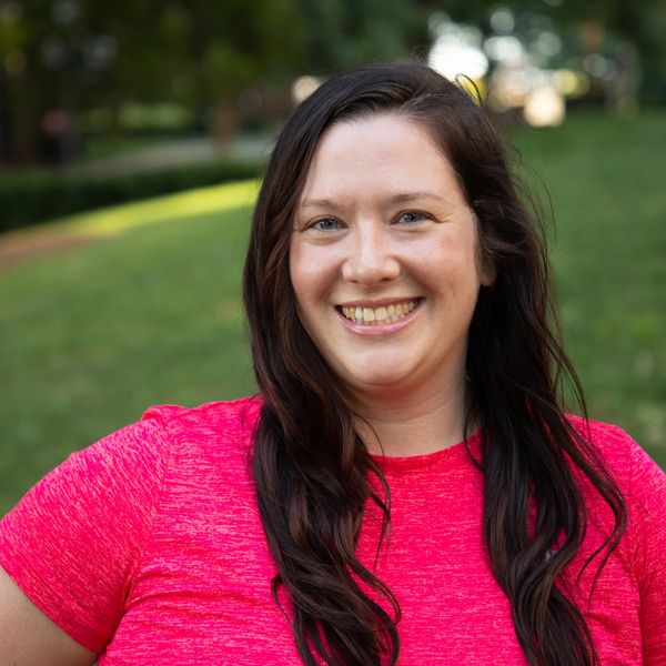 Smiling woman in a red shirt outdoors.