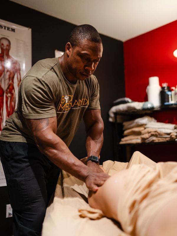 Licensed massage therapist Kiran giving a client a sports massage at his Alpha Omega location.