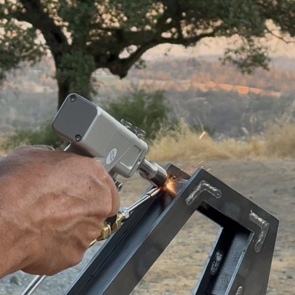 Close-up of a hand welding metal outdoors with a torch.