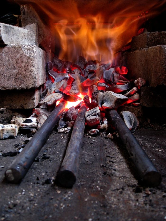 There are three pieces of steel heating up in a charcoal forge.