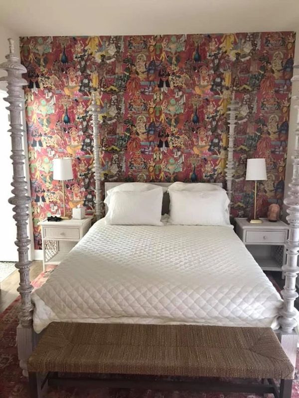Fun ethnic wallpaper is the backdrop for a beautiful white four-poster bed layered with white linens