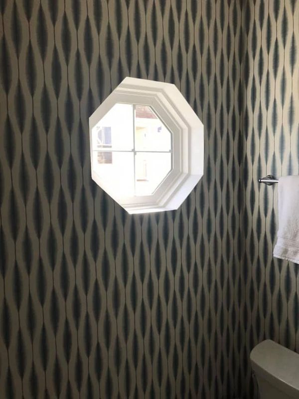 A porthole window is surrounded by geometric patterned wallpaper