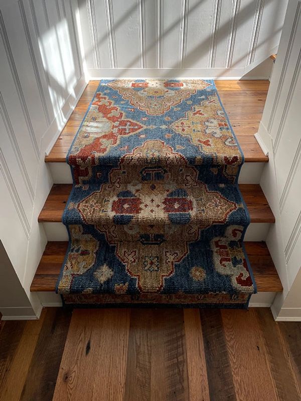 A wool stair runner with muted soumak colors complements historic hardwood floors