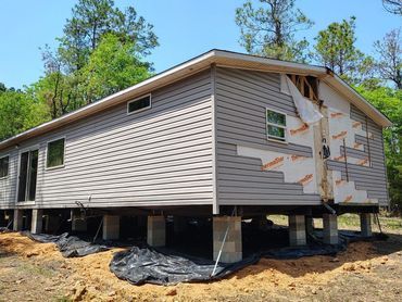 A raised mobile home under construction with exposed insulation.