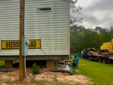 A house being moved with an 'Oversize Load' sign on it.