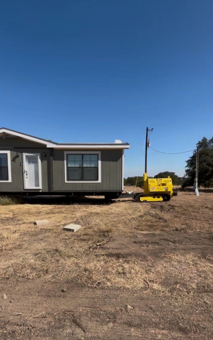 A mobile home being moved by a yellow tracked vehicle.