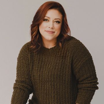Woman in a brown sweater smiling.