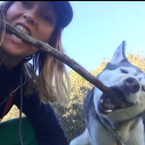 Woman and dog playing with a stick together.