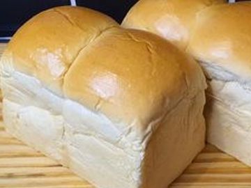 Freshly baked soft white bread loaves on a wooden surface.