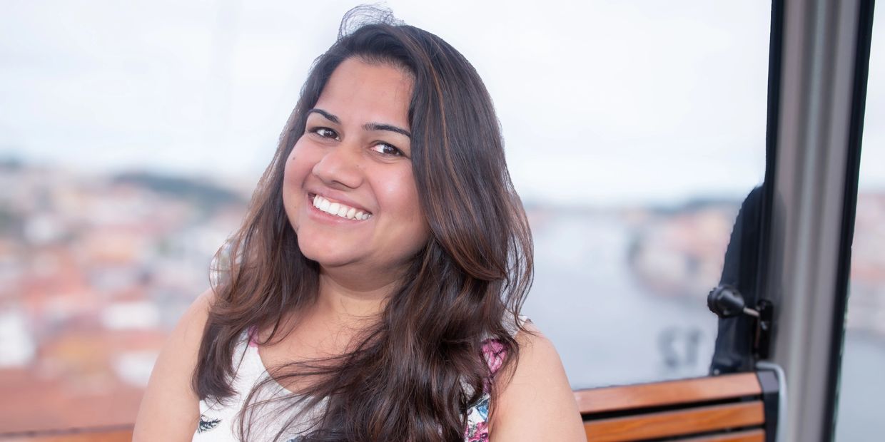 Smiling woman with long hair sitting on a wooden bench inside a cable car.