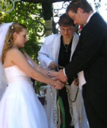 A couple performing the rite of handfasting during their wedding ceremony