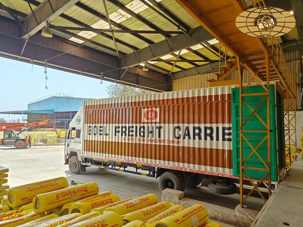 A freight truck parked inside a warehouse with yellow insulation rolls.