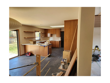 "Basement kitchenette under construction with new cabinets, countertops, and tile flooring.