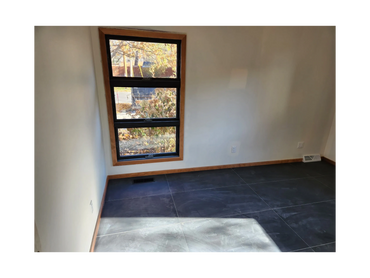Basement room with newly installed drywall, window trim, and fresh flooring, ready for use.