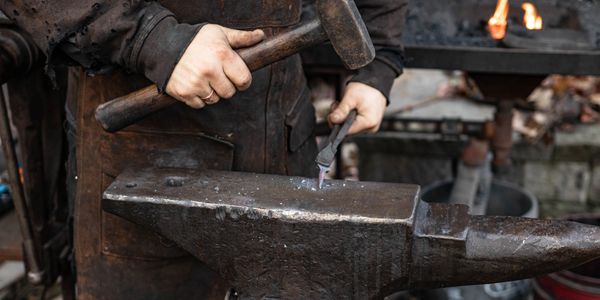 Blacksmith shaping heated metal on an anvil.